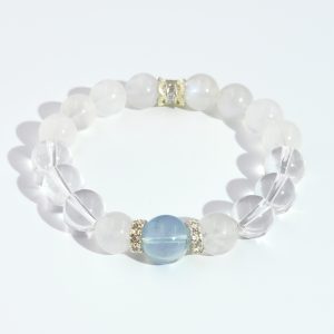 Soft Mist Blue bracelet with phantom blue moonstone centerpiece and clear quartz beads, photographed on a smooth white surface