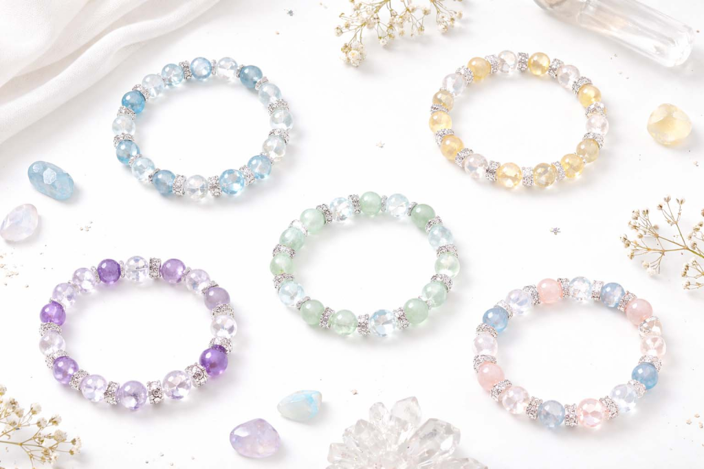 Pastel crystal bracelets on a clean white background, styled in a minimalist jewelry flat lay.